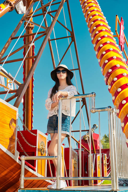 站在游乐场海盗船旁边的美女图片