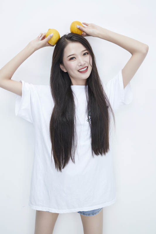 手拿柠檬身穿白色长T血的亚洲可爱少女人像图片