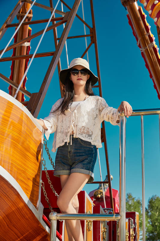 站在游乐场海盗船旁边的美女图片