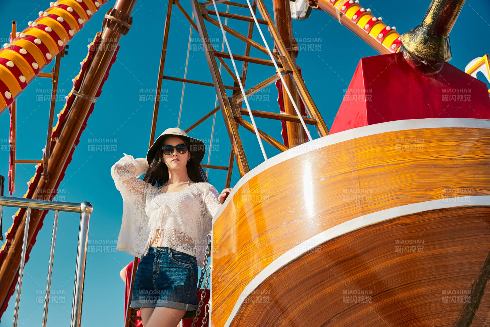 站在游乐场海盗船旁边的美女图片