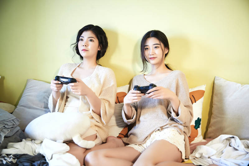 坐在床上打电玩的俩位美女图片