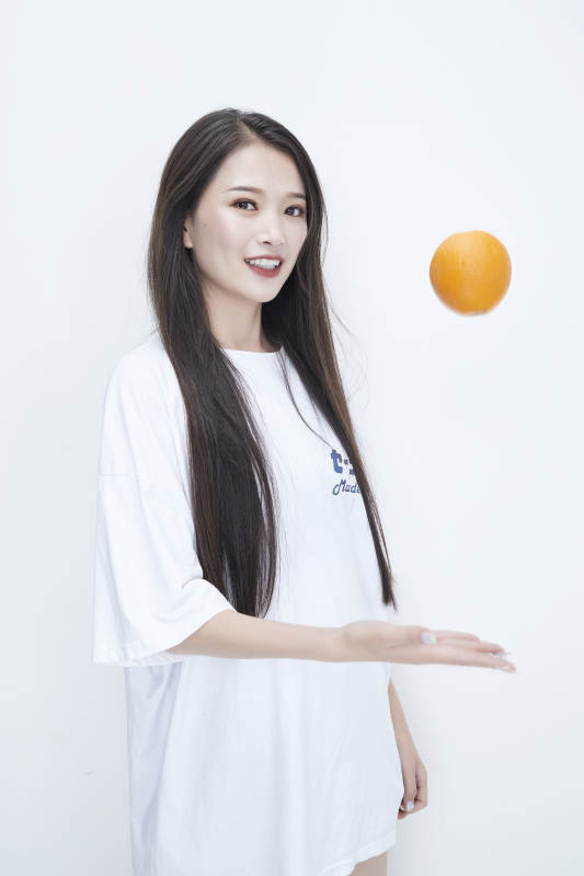玩耍橙子穿白色长T血的亚洲可爱少女人像图片