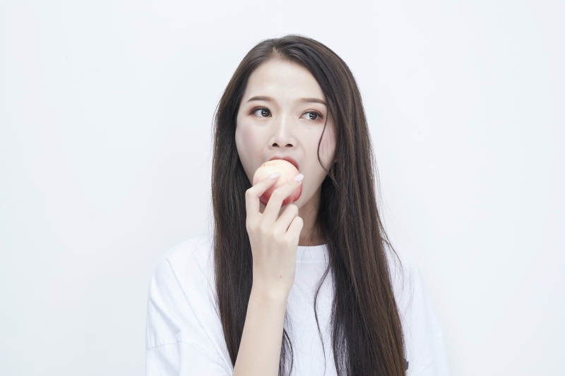 吃桃子的穿白色长T血衫的长发可爱少女人像图片