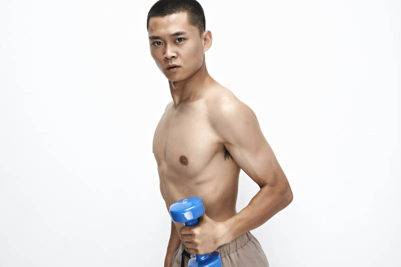 使用哑铃进行健身锻炼的亚洲男性图片
