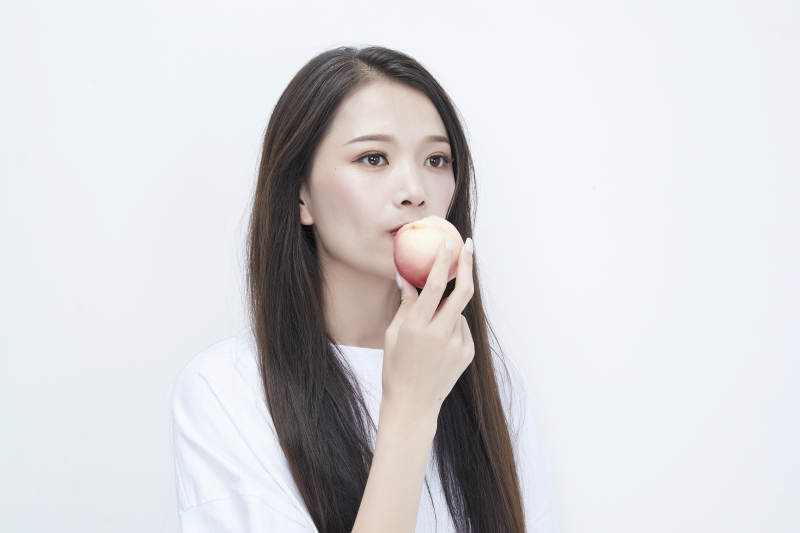 吃桃子的穿白色长T血衫的长发可爱少女人像图片