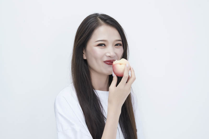 吃桃子的穿白色长T血衫的长发可爱少女人像图片