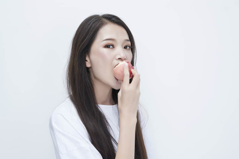 吃桃子的穿白色长T血衫的长发可爱少女人像图片