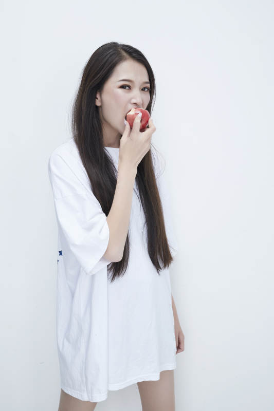 吃桃子的穿白色长T血衫的长发可爱少女人像图片