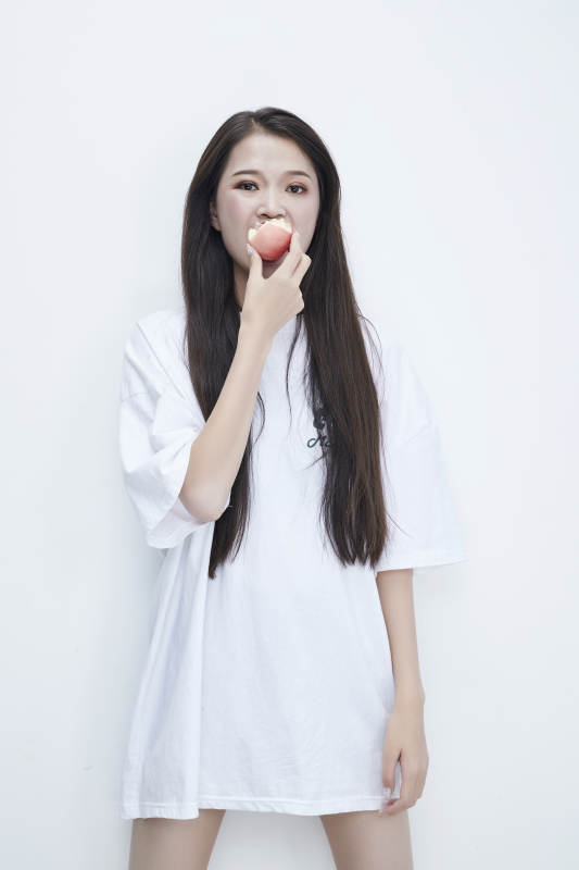 吃桃子的穿白色长T血衫的长发可爱少女人像图片