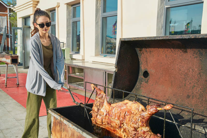 在翻转烤炉内烤全羊的美女图片