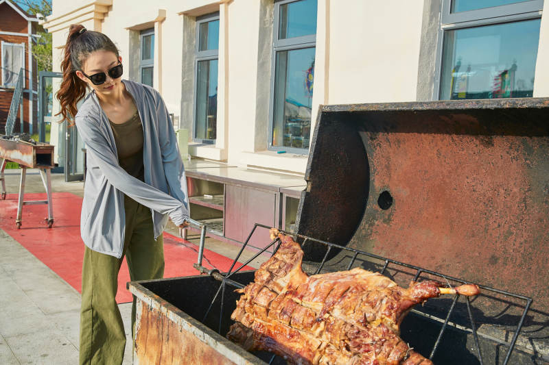 在翻转烤炉内烤全羊的美女图片