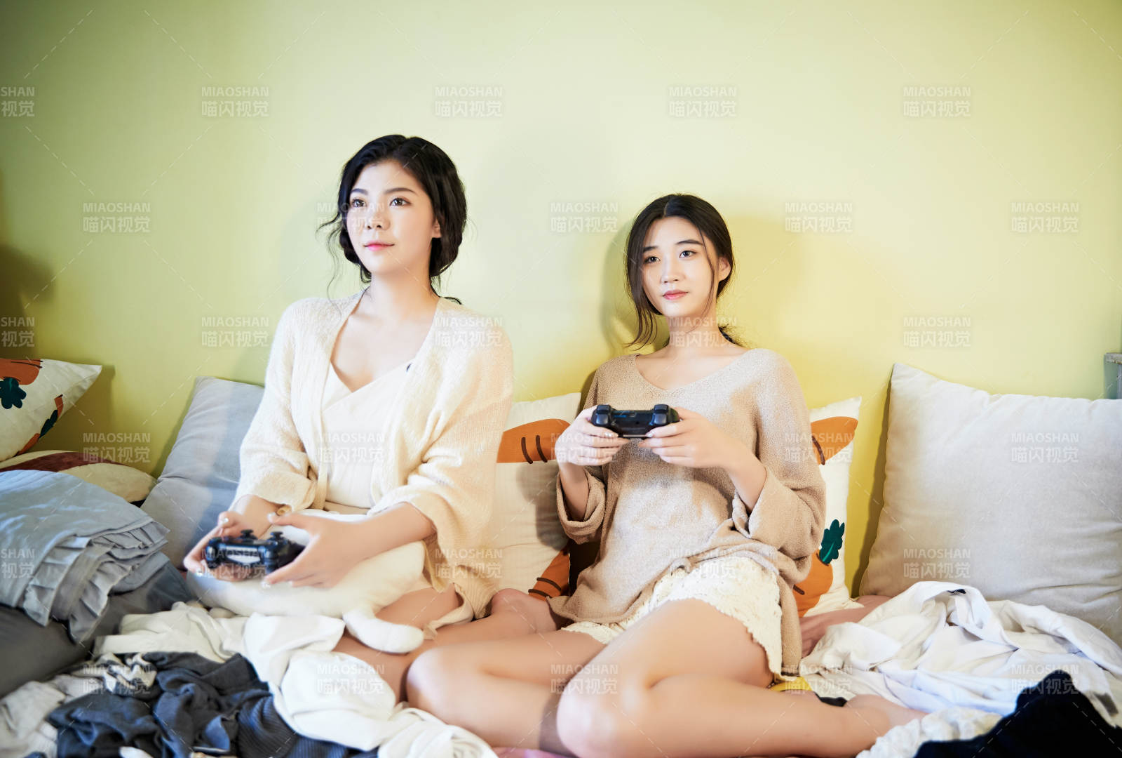 坐在床上打电玩的俩位美女图片