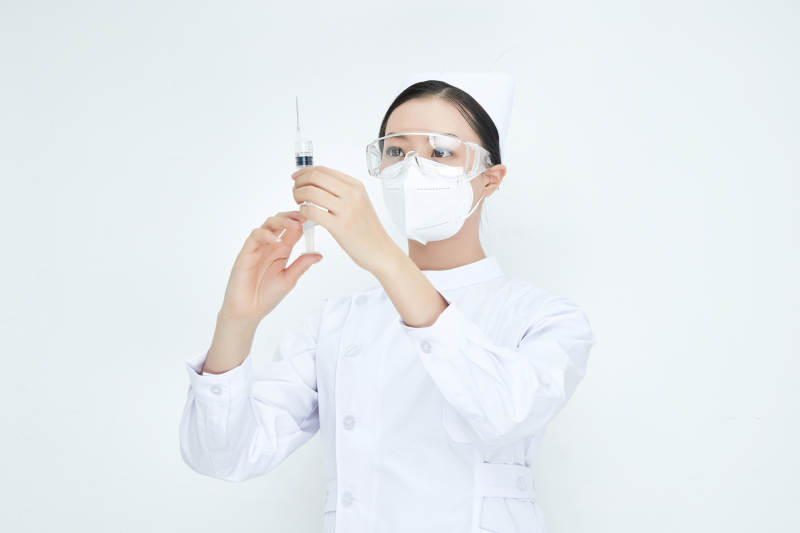 穿护士服戴口罩手执针筒的年轻女护士图片