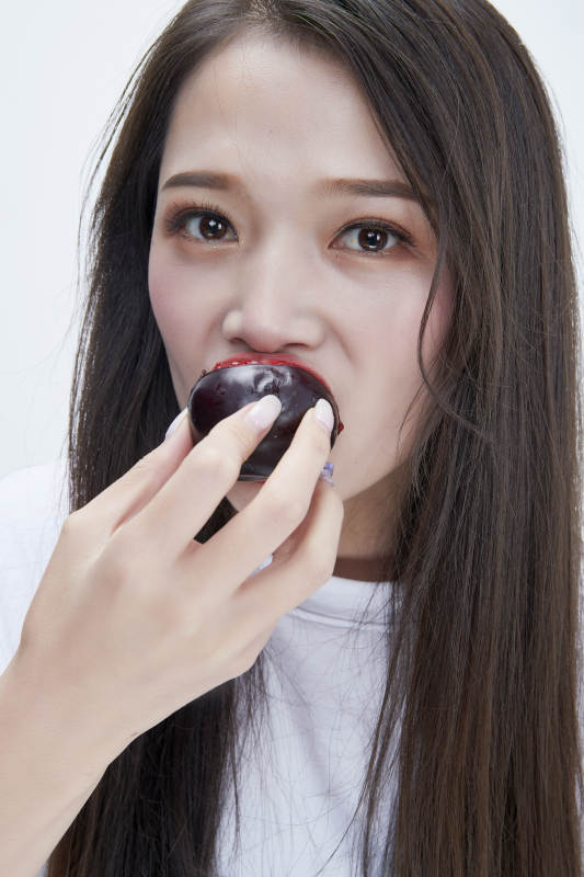 吃黑李子穿白色长T血衫的长发可爱少女人像图片