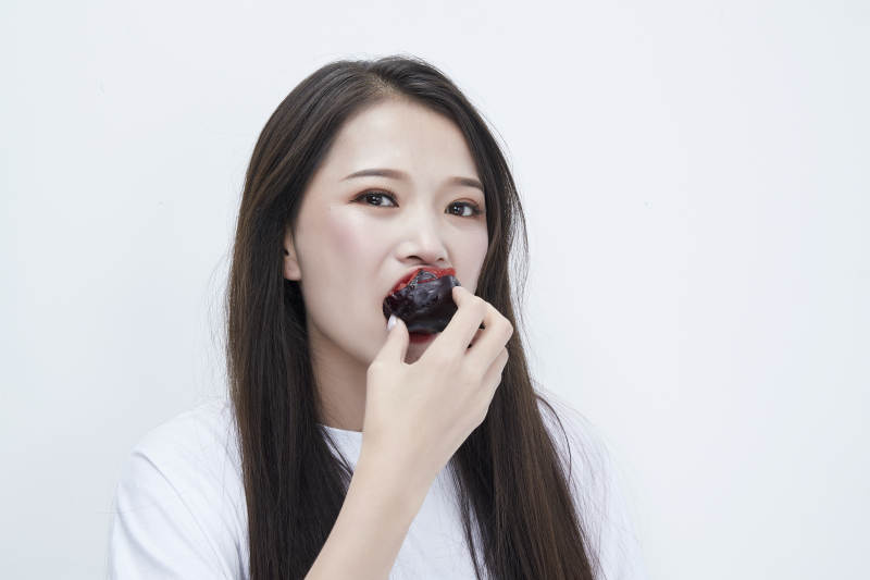 吃黑李子穿白色长T血衫的长发可爱少女人像图片