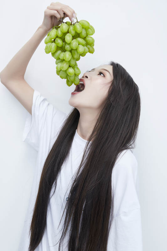 吃葡萄的穿白色长T血衫的长发可爱少女人像图片