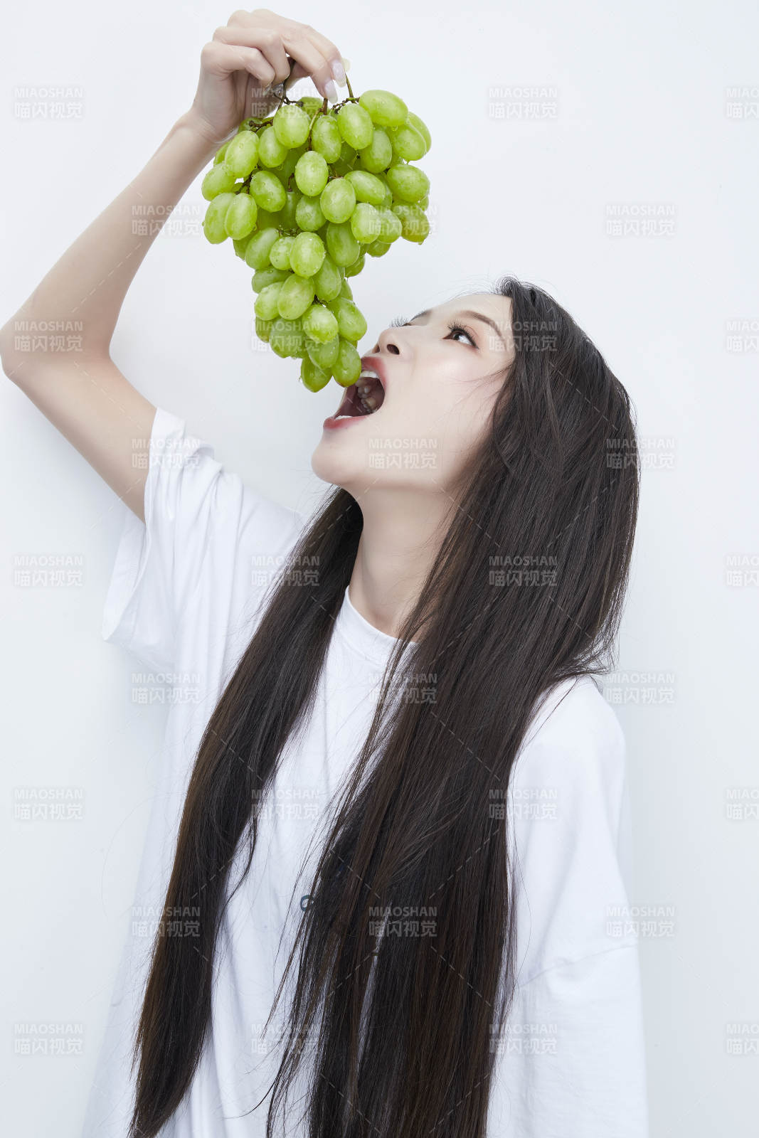 吃葡萄的穿白色长T血衫的长发可爱少女人像图片