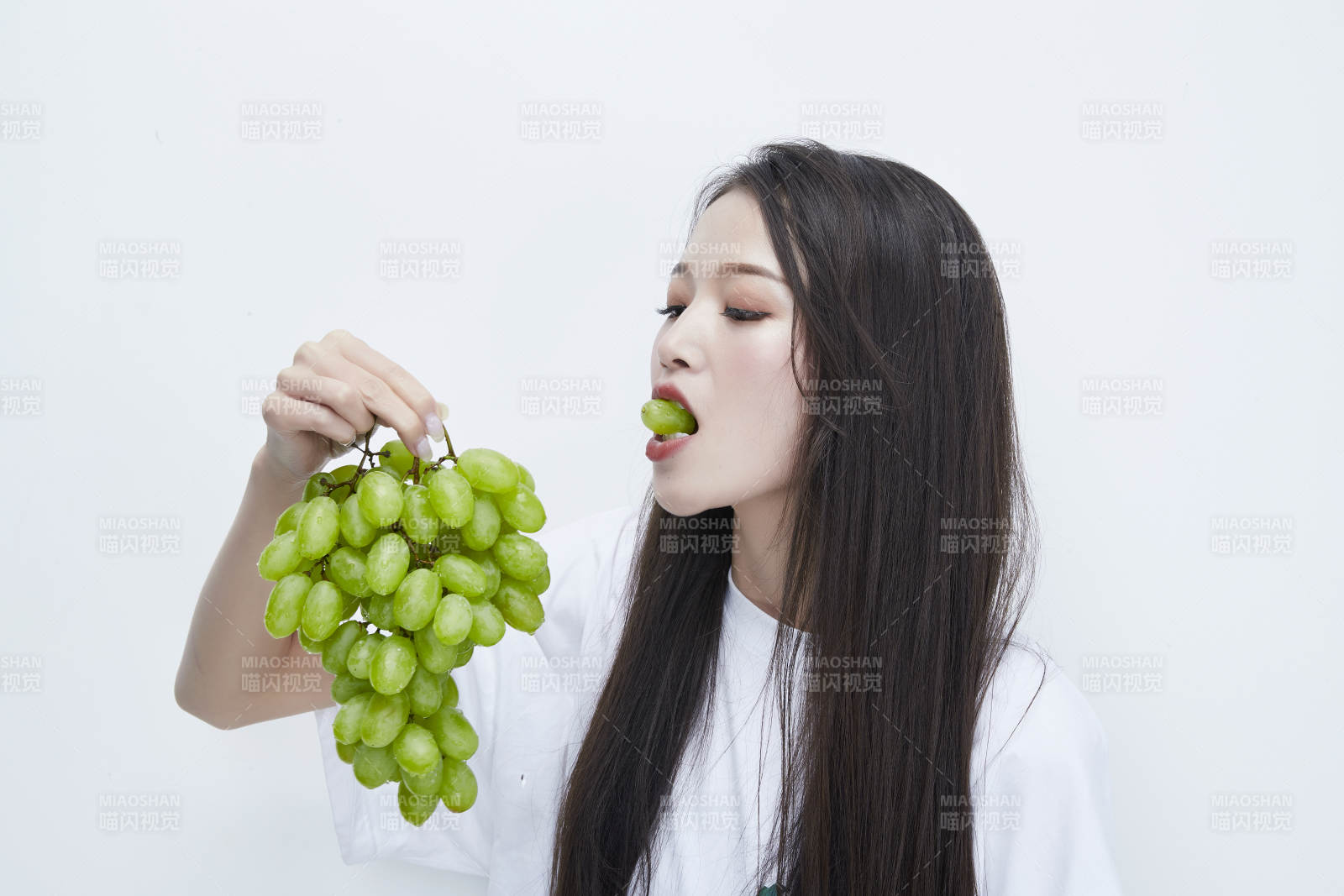 吃葡萄的穿白色长T血衫的长发可爱少女人像图片