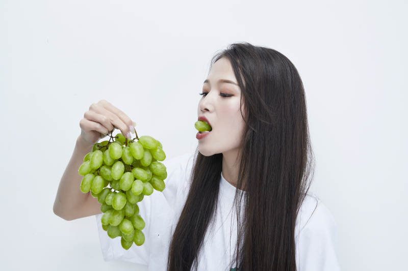 吃葡萄的穿白色长T血衫的长发可爱少女人像图片