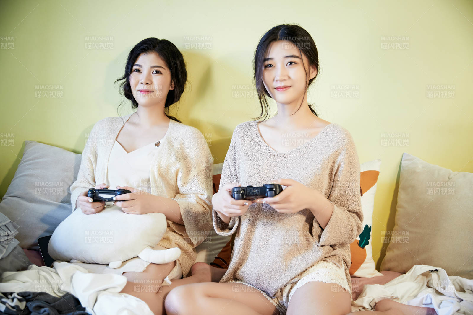 坐在床上打电玩的俩位美女图片