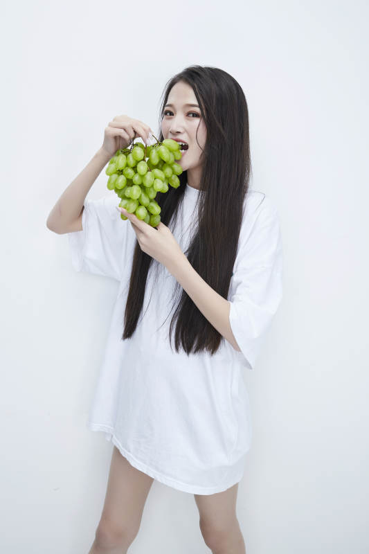 吃葡萄的穿白色长T血衫的长发可爱少女人像图片