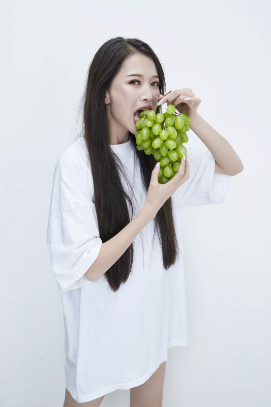 吃葡萄的穿白色长T血衫的长发可爱少女人像图片