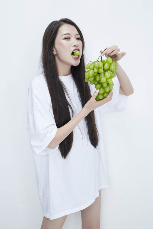 吃葡萄的穿白色长T血衫的长发可爱少女人像图片