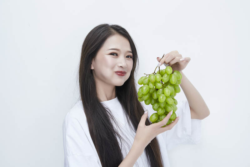 吃葡萄的穿白色长T血衫的长发可爱少女人像图片