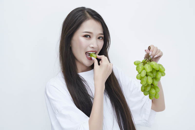 吃葡萄的穿白色长T血衫的长发可爱少女人像图片