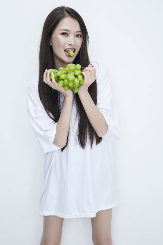 吃葡萄的穿白色长T血衫的长发可爱少女人像图片