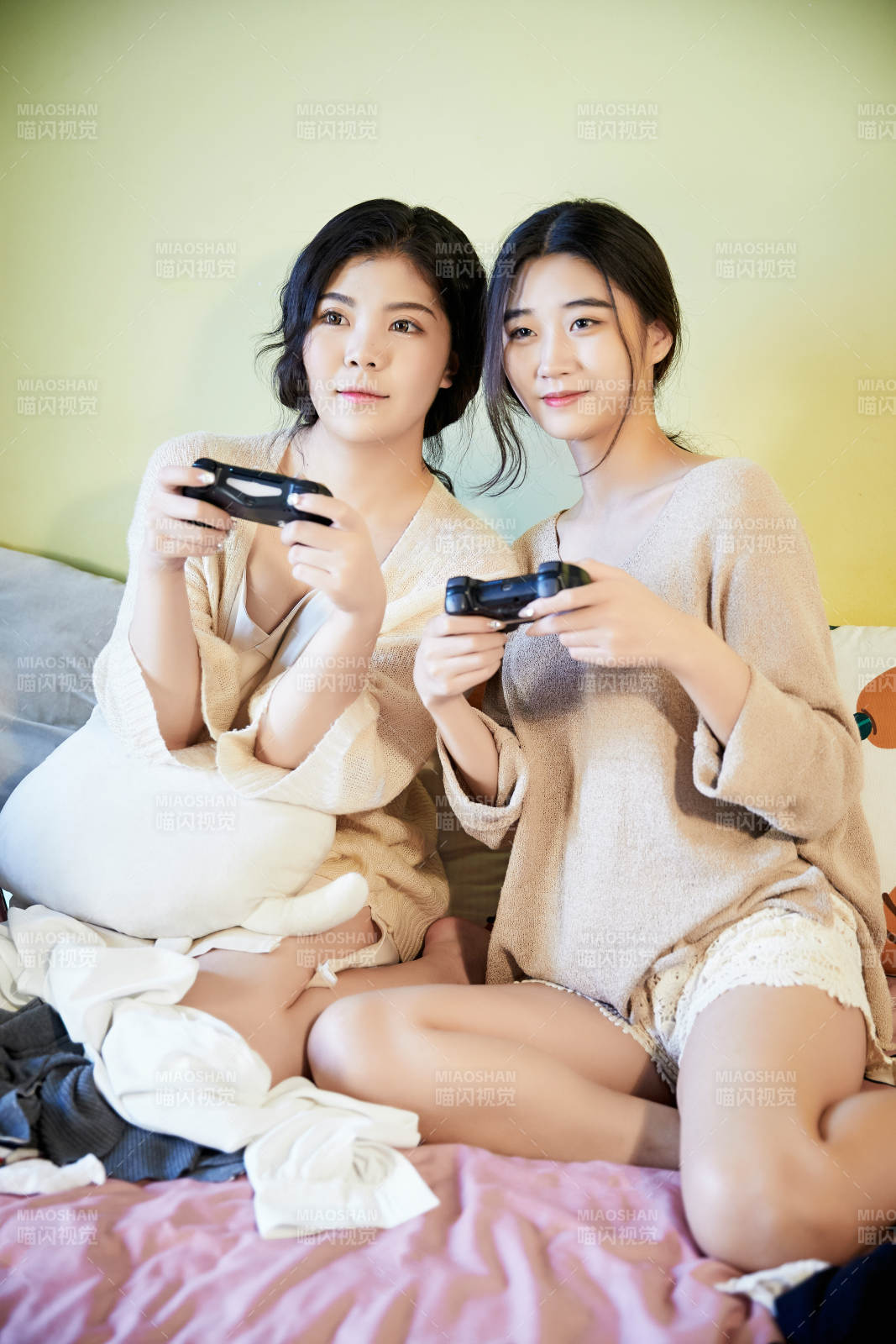 坐在床上打电玩的俩位美女图片