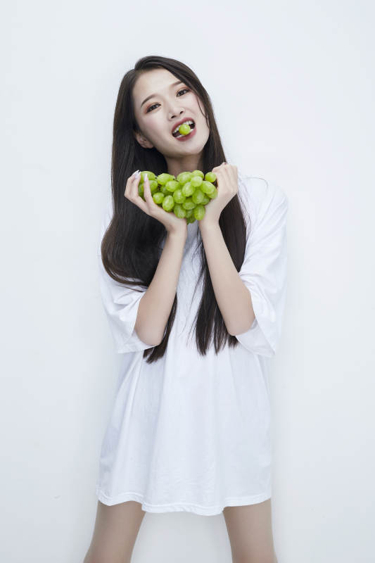 吃葡萄的穿白色长T血衫的长发可爱少女人像图片