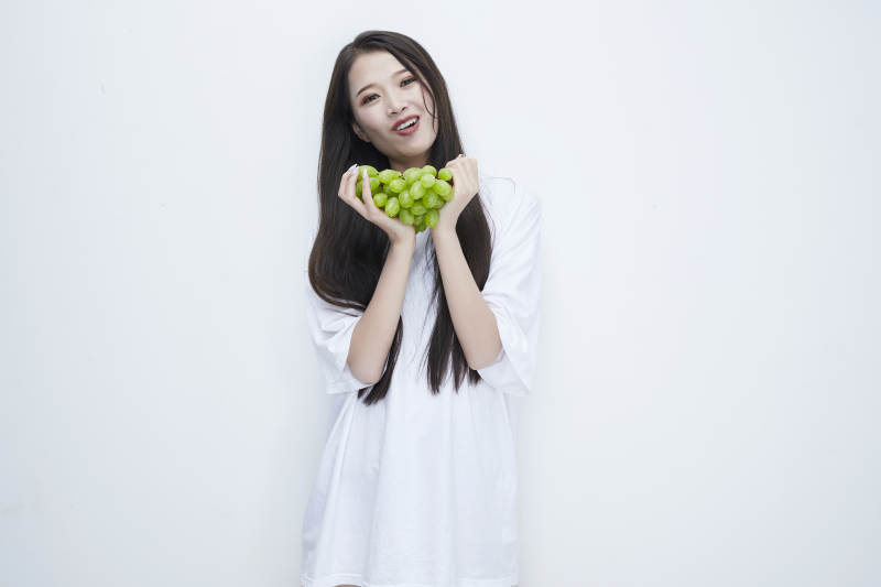 吃葡萄的穿白色长T血衫的长发可爱少女人像图片