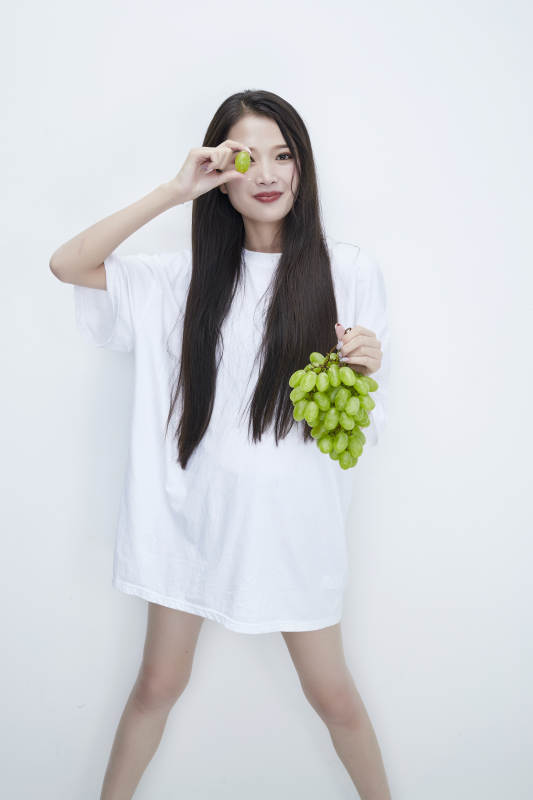 吃葡萄的穿白色长T血衫的长发可爱少女人像图片
