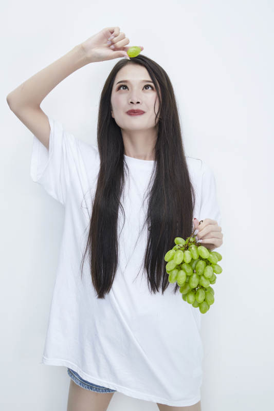吃葡萄的穿白色长T血衫的长发可爱少女人像图片