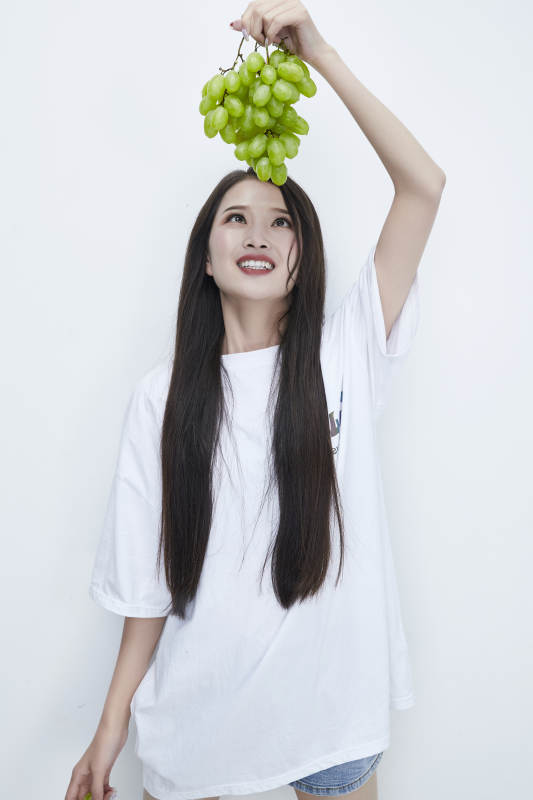 吃葡萄的穿白色长T血衫的长发可爱少女人像图片