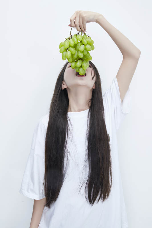 吃葡萄的穿白色长T血衫的长发可爱少女人像图片
