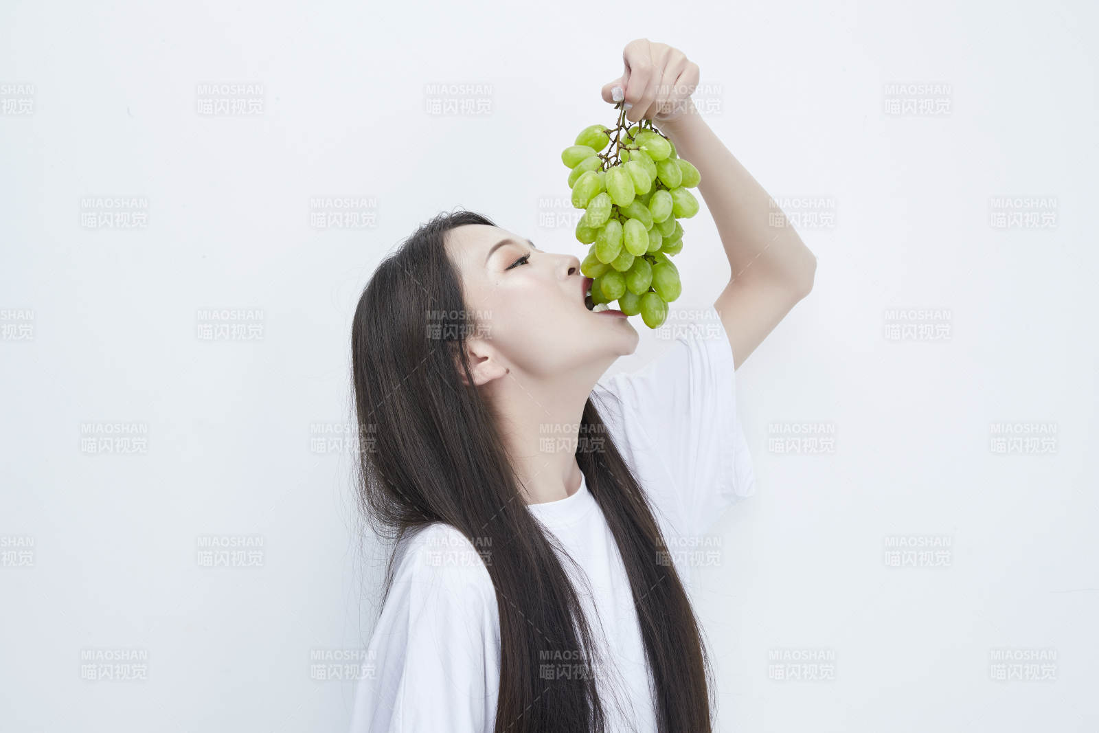 吃葡萄的穿白色长T血衫的长发可爱少女人像图片