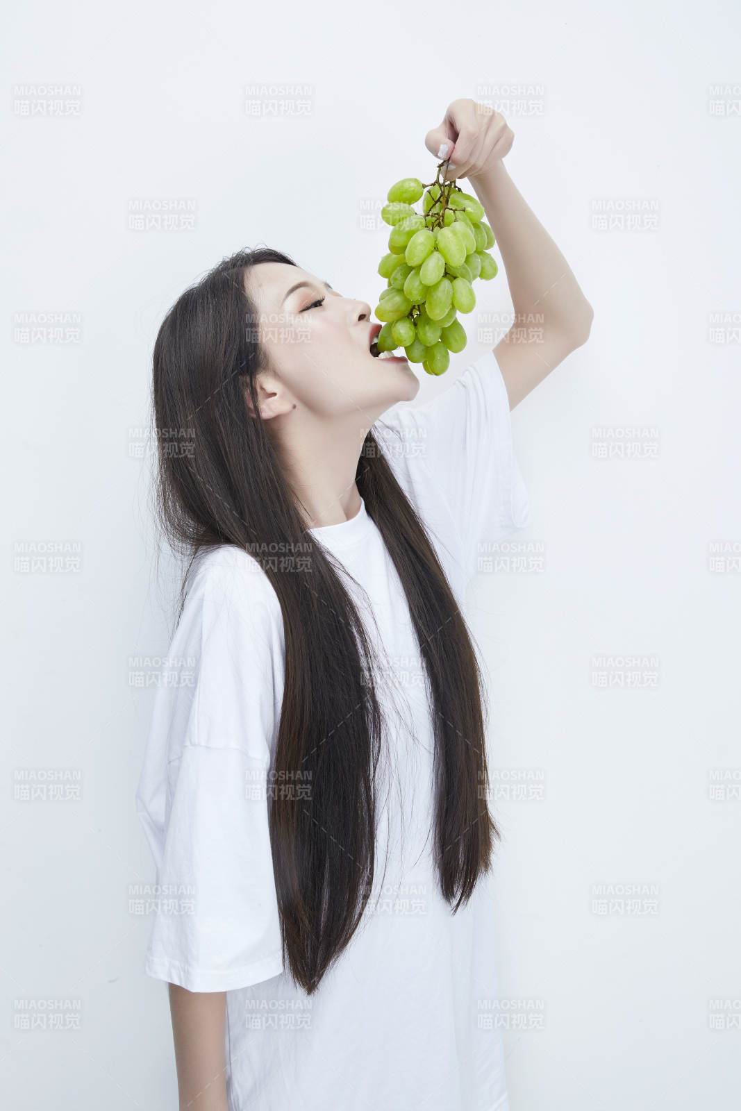 吃葡萄的穿白色长T血衫的长发可爱少女人像图片