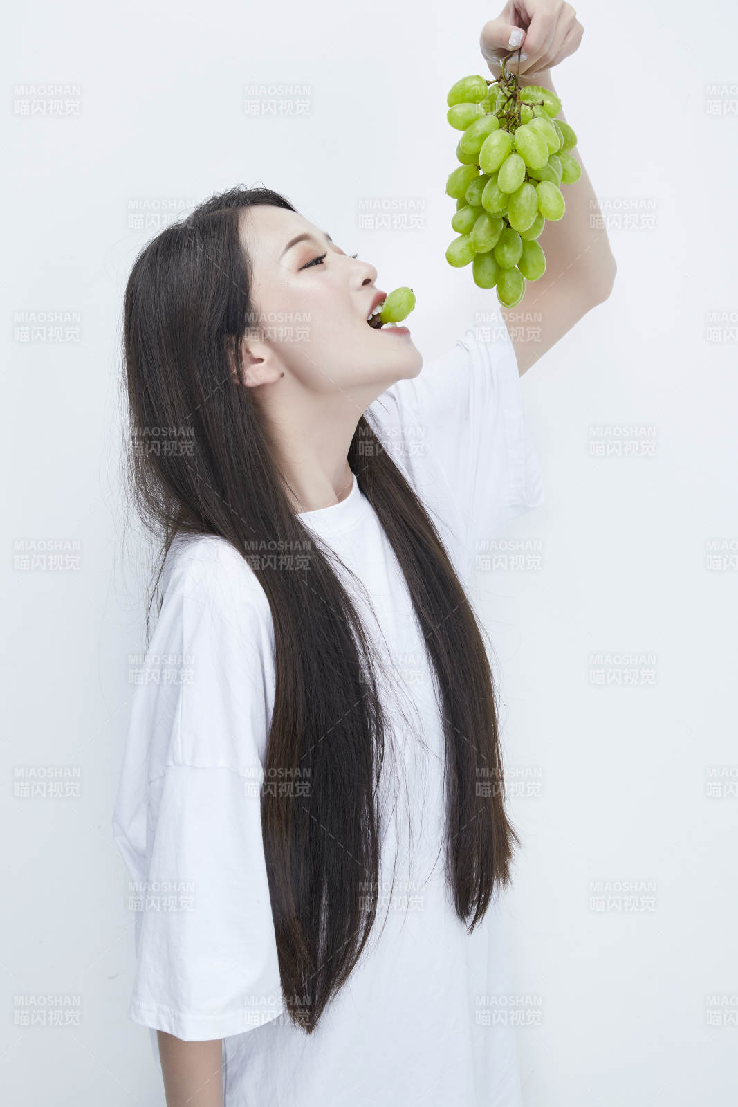 吃葡萄的穿白色长T血衫的长发可爱少女人像图片