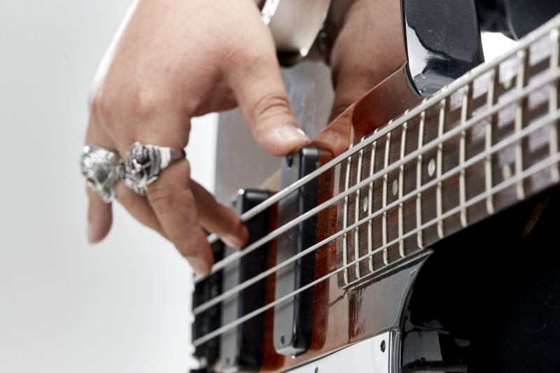 展示贝斯演奏技术技巧的亚洲男性乐手人像局部特写图片