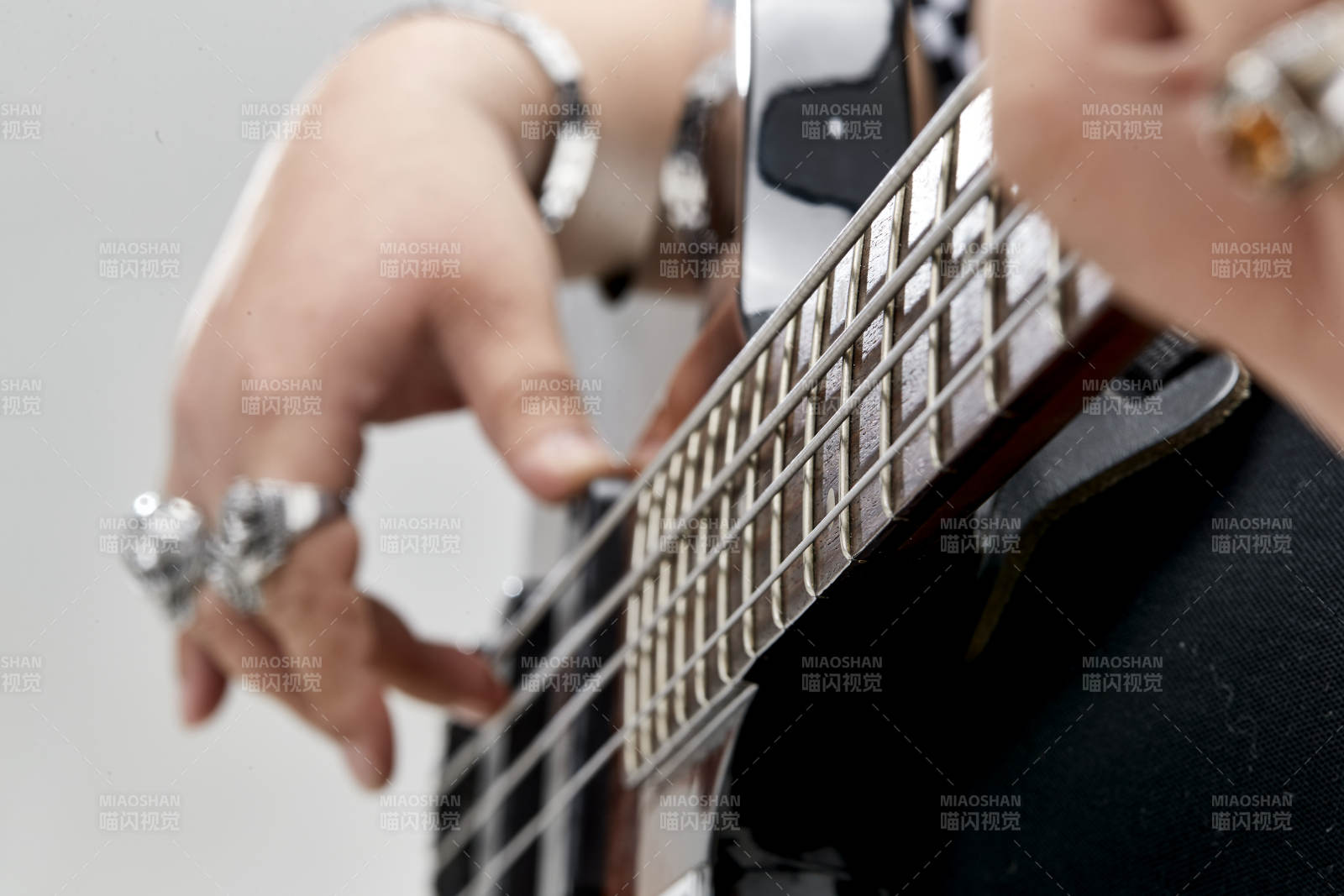 展示贝斯演奏技术技巧的亚洲男性乐手人像局部特写图片