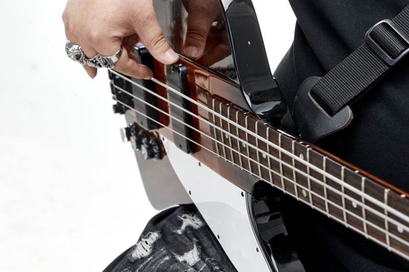 展示贝斯演奏技术技巧的亚洲男性乐手人像局部特写图片