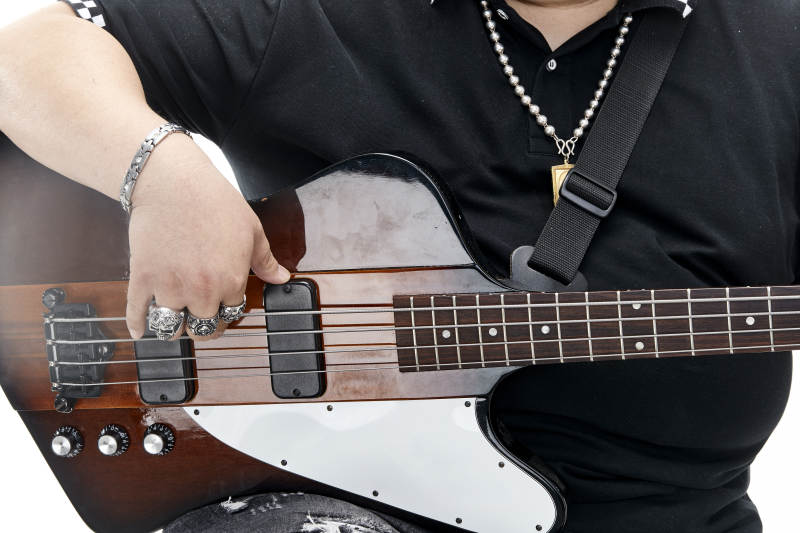 展示贝斯演奏技术技巧的亚洲男性乐手人像局部特写图片