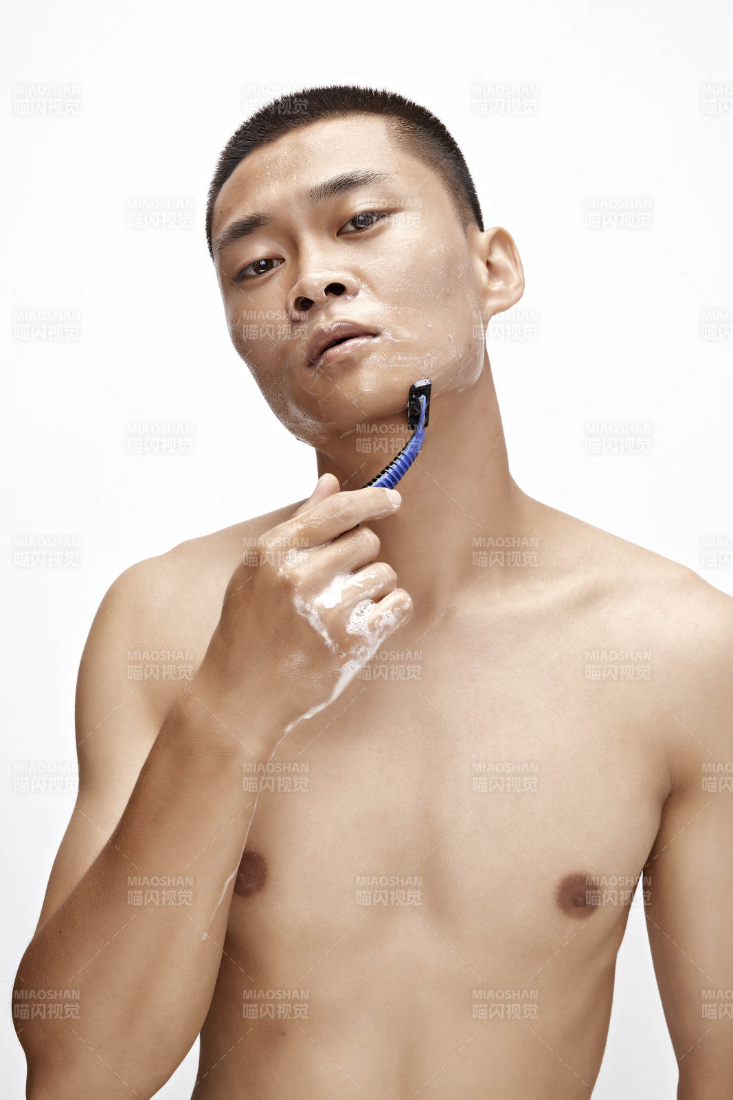 白色背景下手持剃须刀在刮胡子的亚洲男性图片
