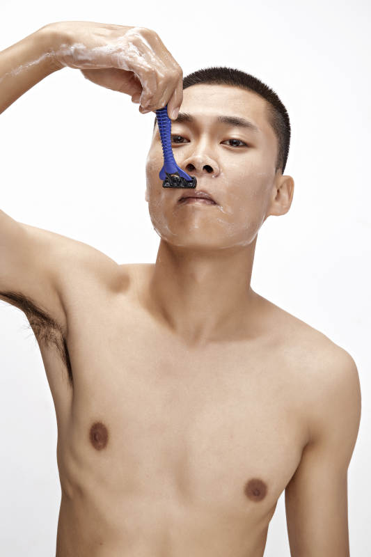 白色背景下手持剃须刀在刮胡子的亚洲男性图片