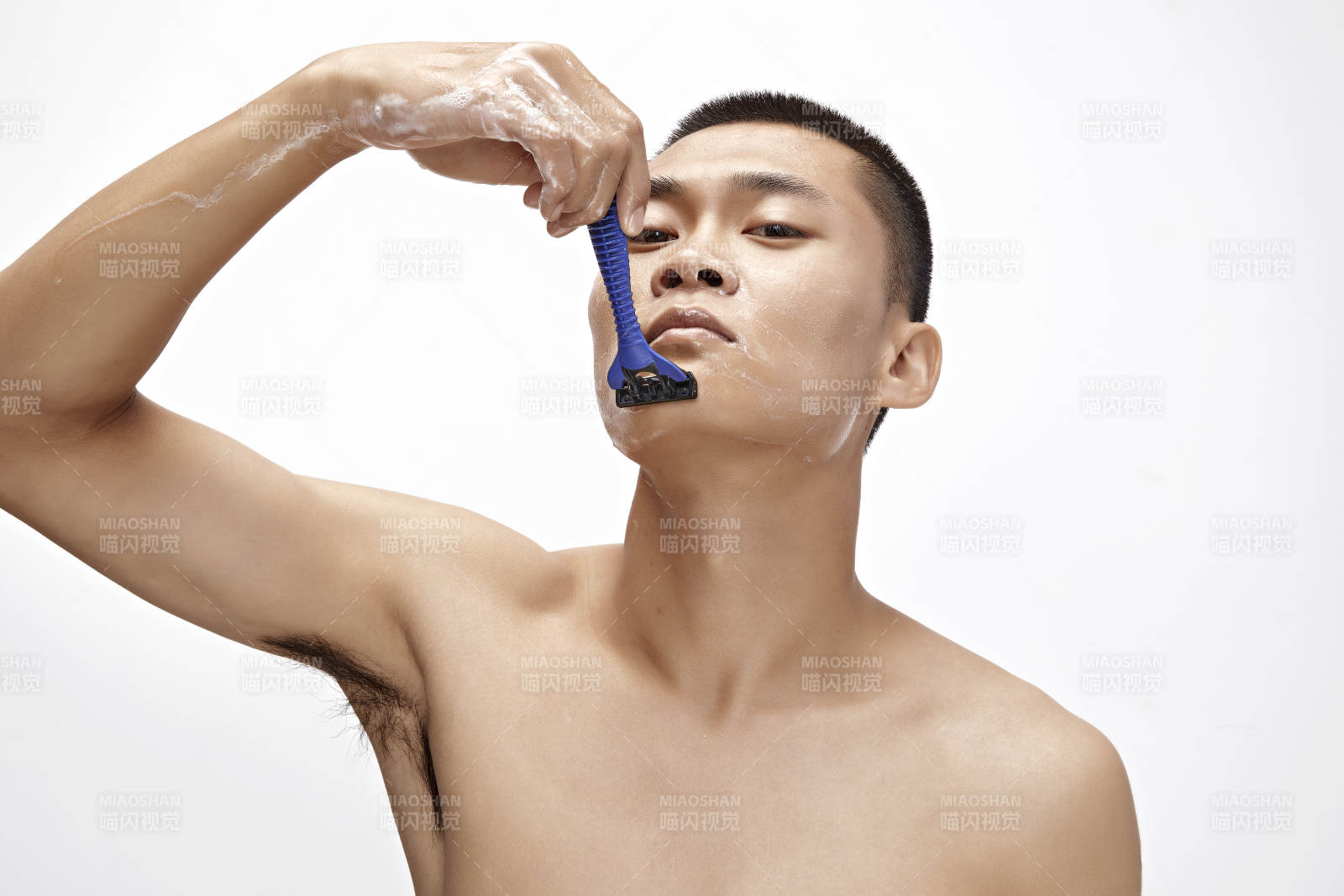 白色背景下手持剃须刀在刮胡子的亚洲男性图片
