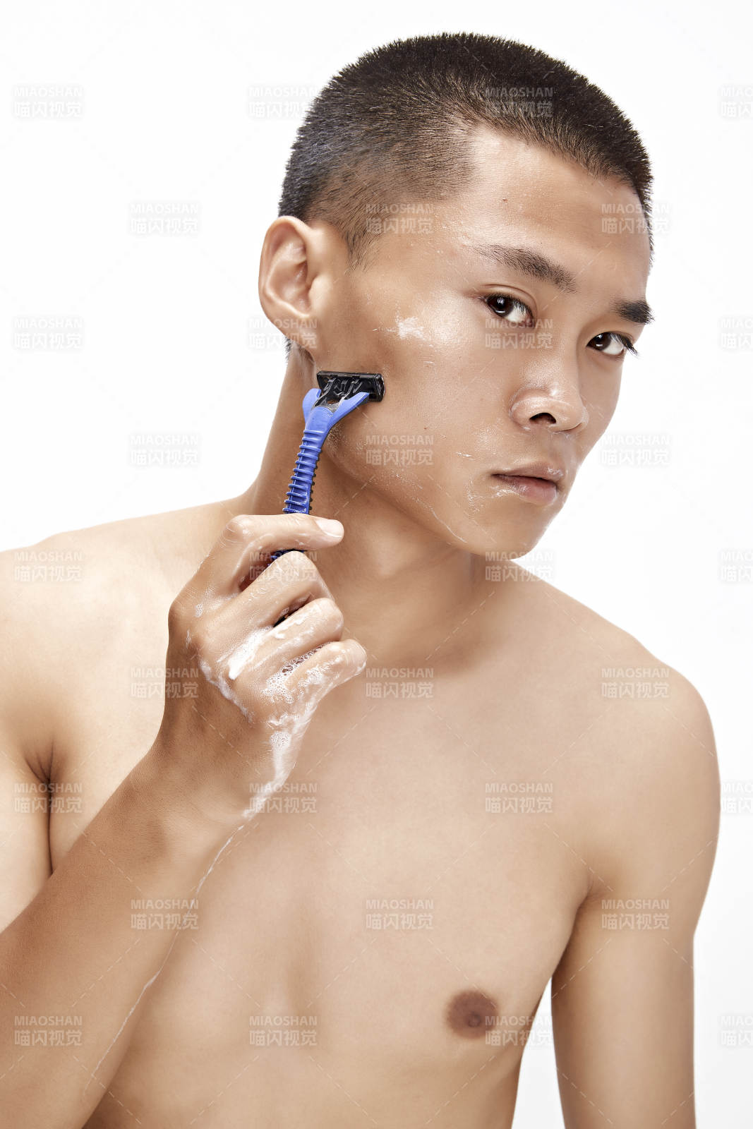 白色背景下手持剃须刀在刮胡子的亚洲男性图片