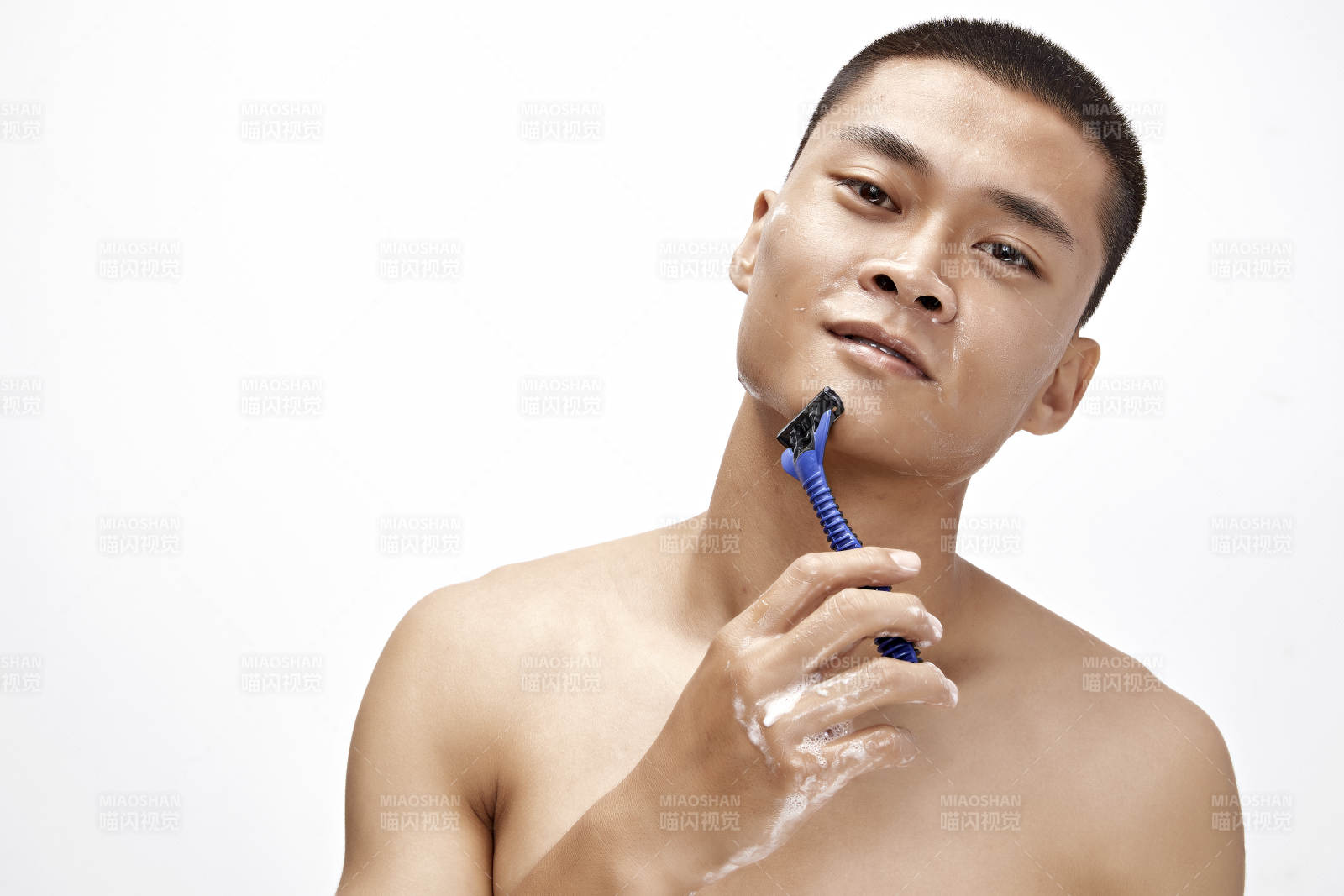 白色背景下手持剃须刀在刮胡子的亚洲男性图片