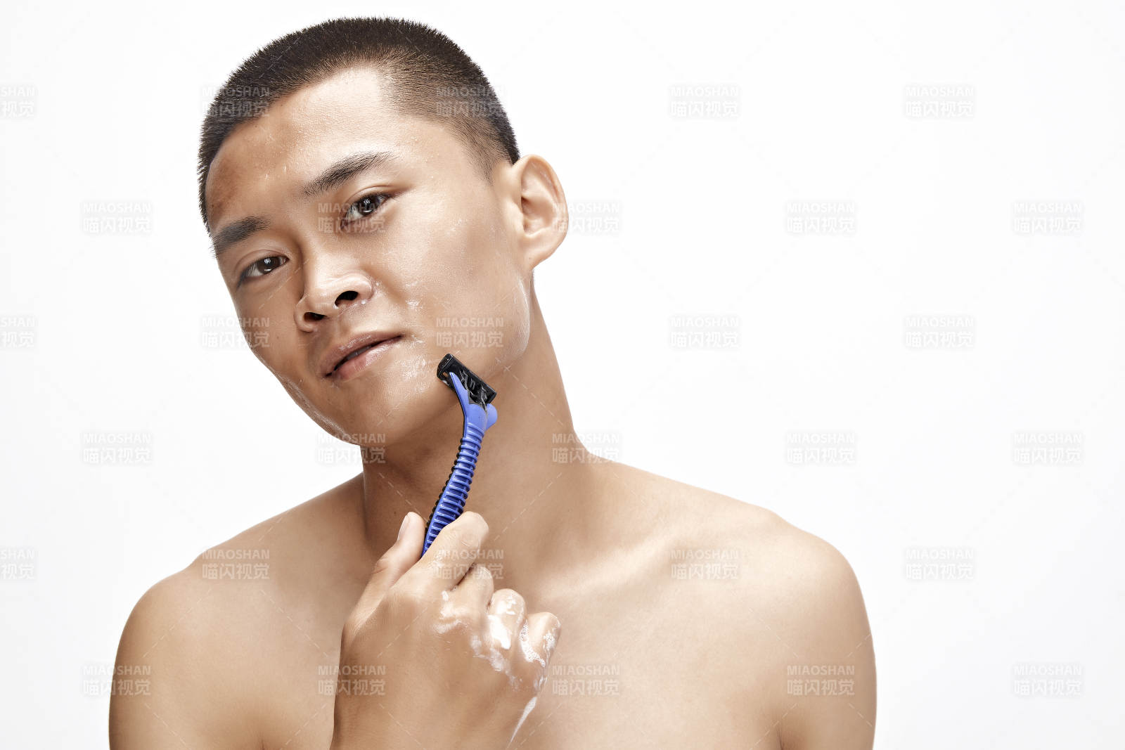 白色背景下手持剃须刀在刮胡子的亚洲男性图片